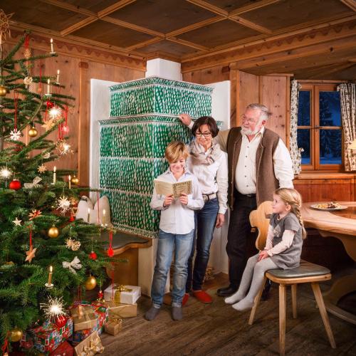 Famiglia in casa vicino alla stufa verde con bambini e albero di Natale