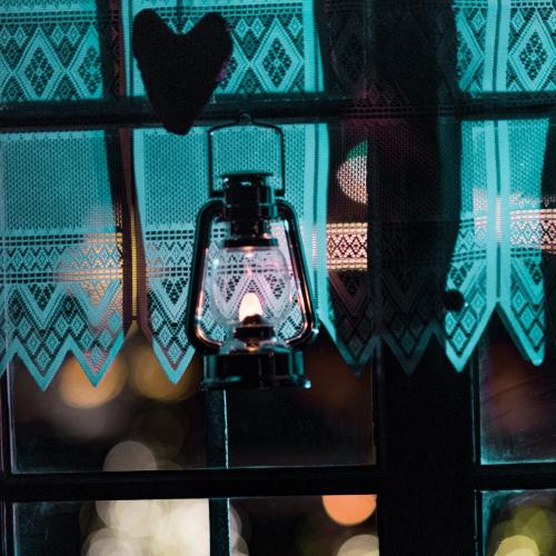 Luci di Natale in Tirolo, una finestra con una lanterna accesa e fuori, luci nel buio
